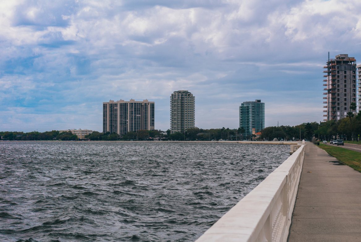 The Bayshore seawall walk beside open bay water, with high-rise towers along the shore