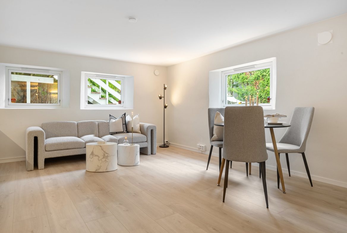 A bright living and dining room with a gray sofa and a small round table