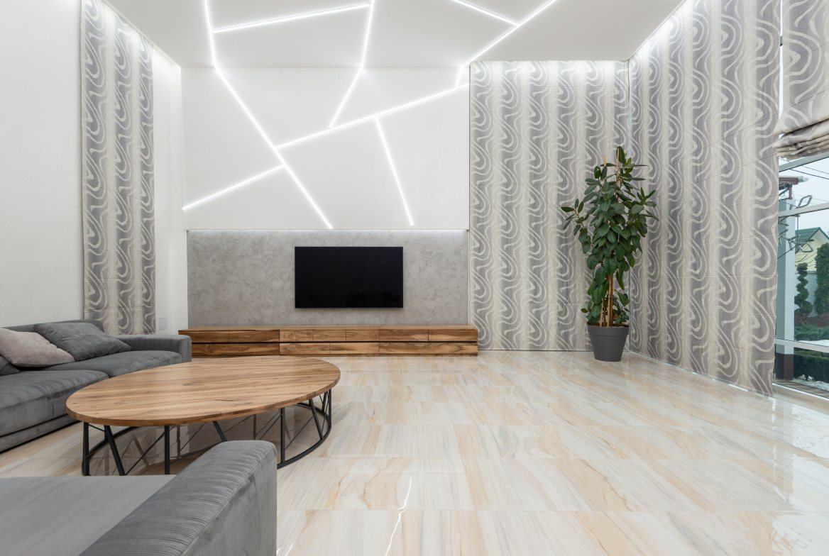 A tall living room with pale stone floors and an oval wood coffee table
