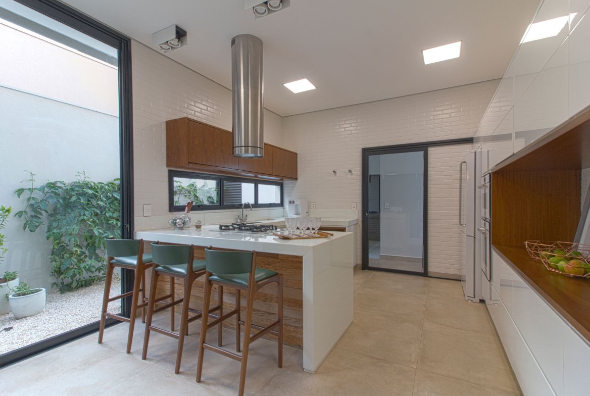 A kitchen island with counter stools beside a floor-to-ceiling window