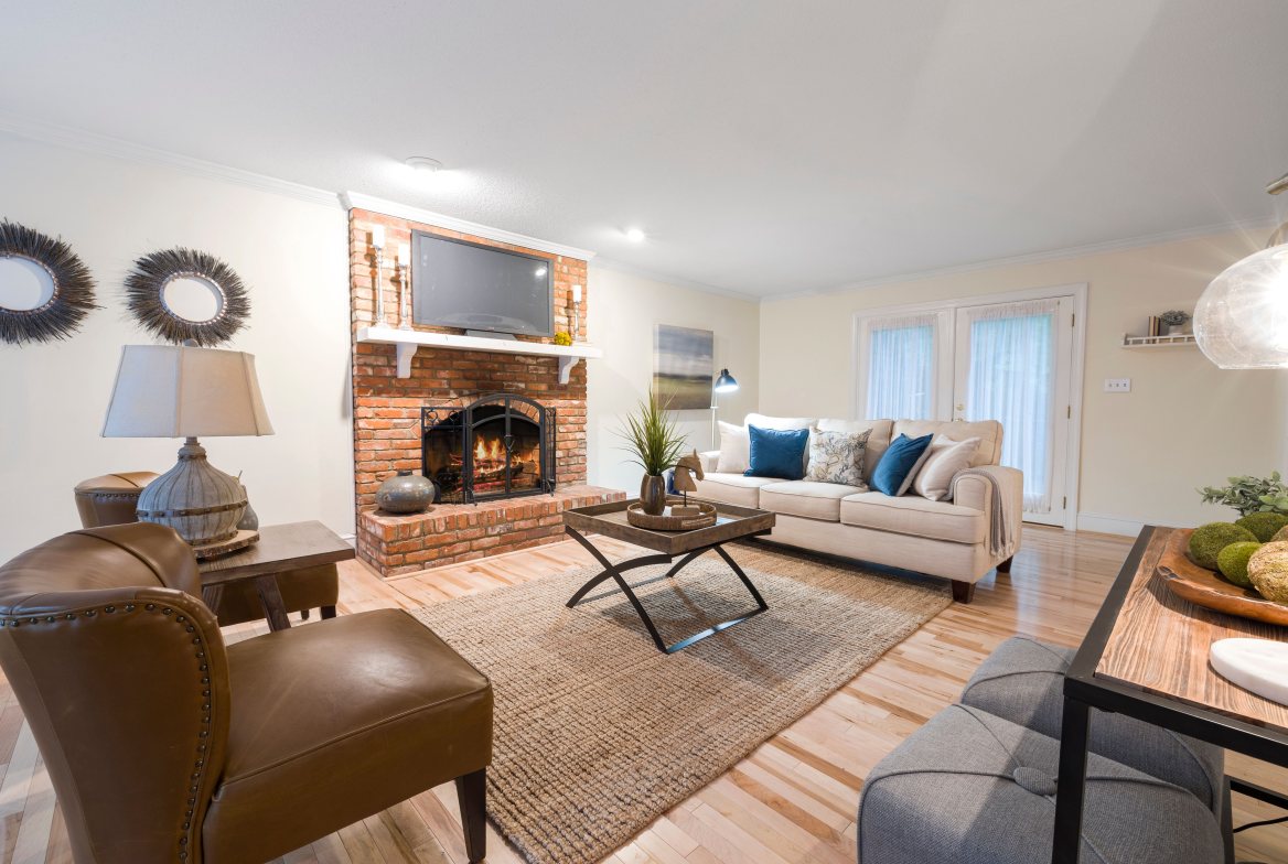 A living room with a brick fireplace and light wood floors