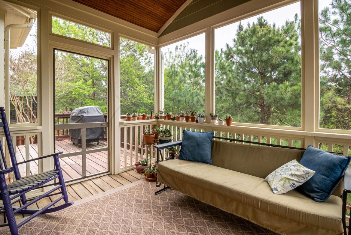 A screened side porch with a sofa and a rocking chair