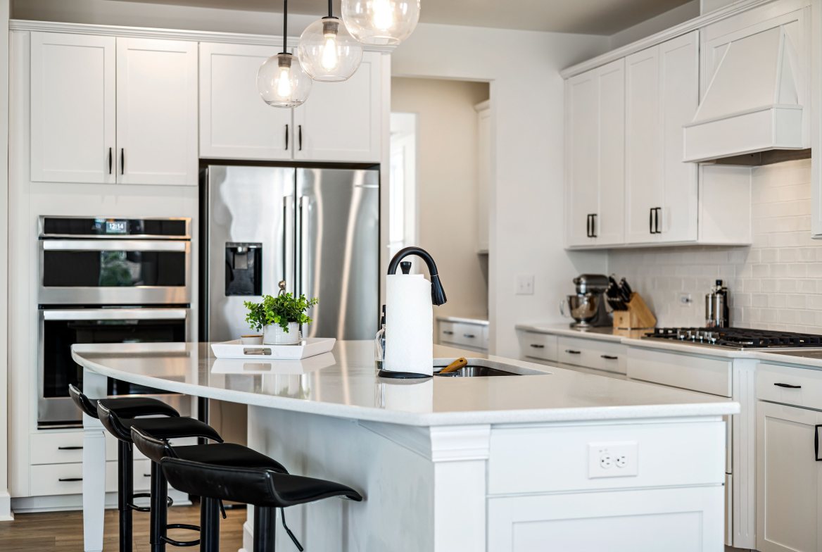 A renovated white kitchen with a large island and black stools
