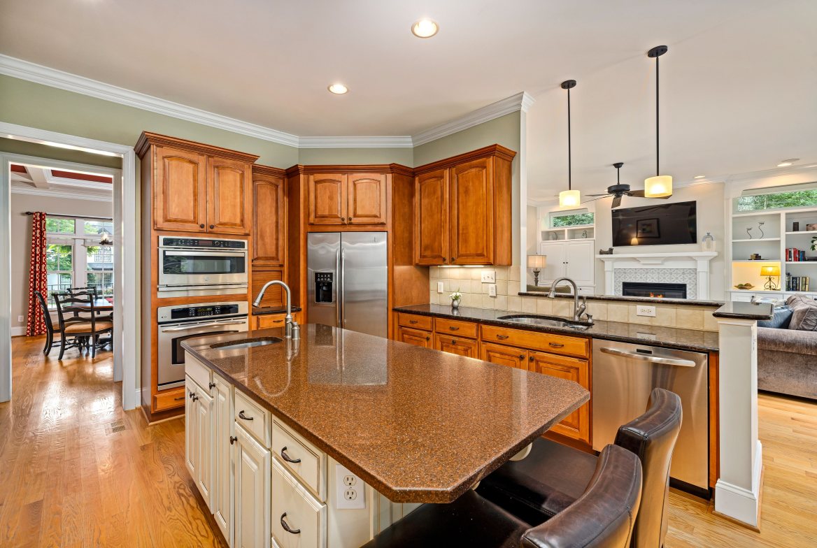 A wood-cabinet kitchen with a granite island, open to the family room