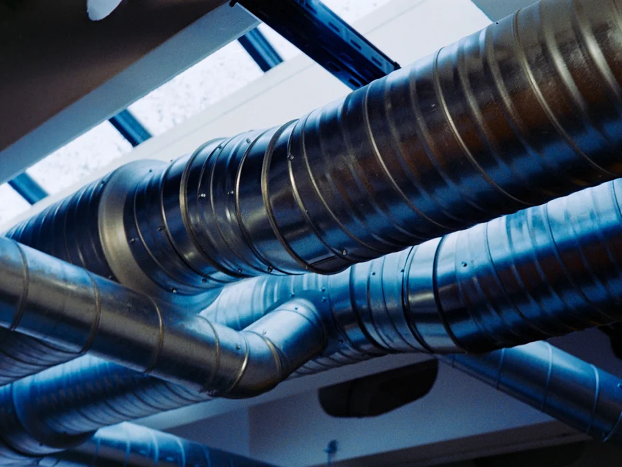 Insulated metal duct runs crossing overhead in cool blue light
