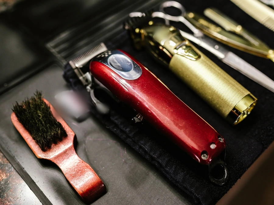 A red clipper, a gold trimmer and a brush laid out in a tray