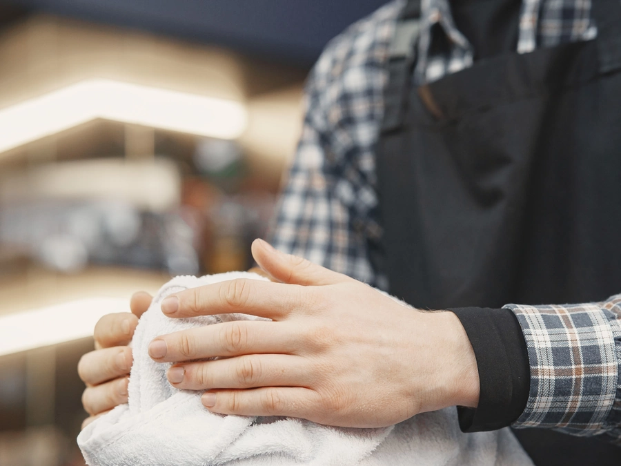 A barber's hands folding a hot towel