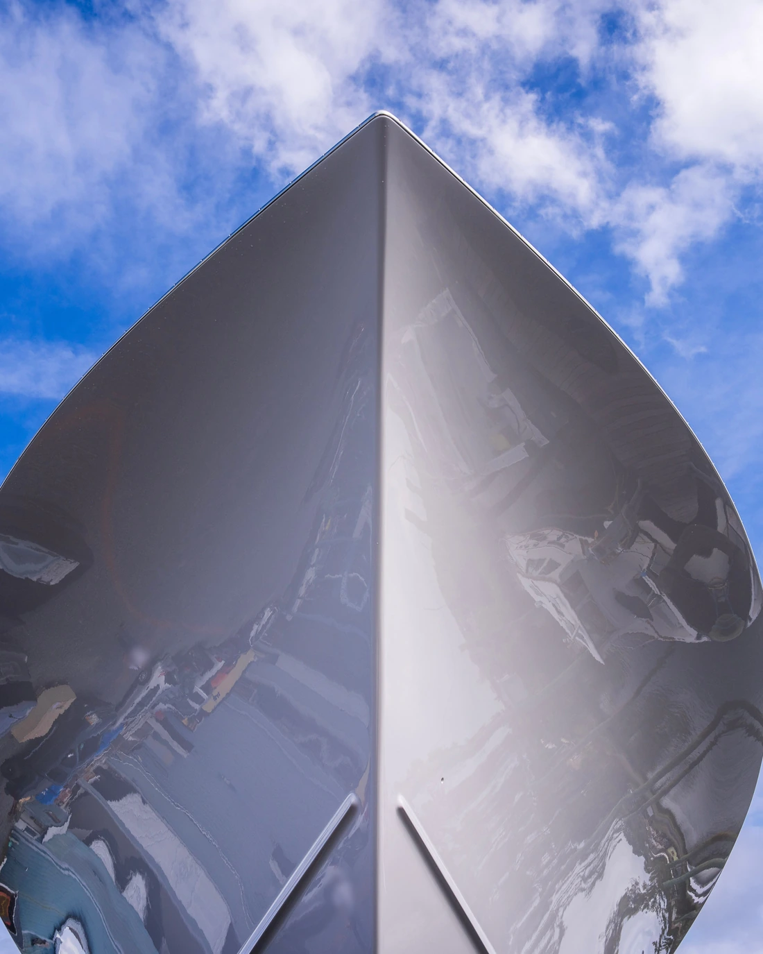 Polished silver boat bow against a blue sky