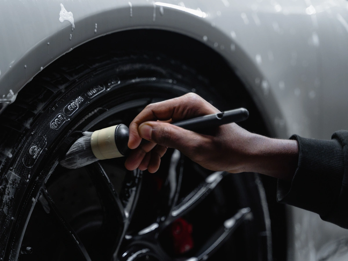Detailer scrubbing a tire and wheel with a brush
