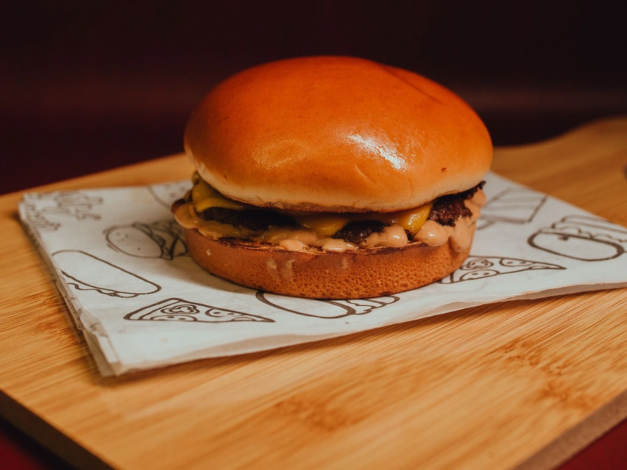 A cheeseburger on a brioche bun, on paper over a wood board