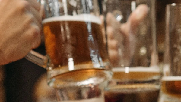 Glass mugs of beer raised together in a toast