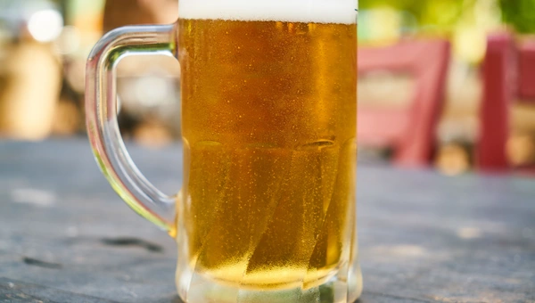A tall mug of cold beer on an outdoor table
