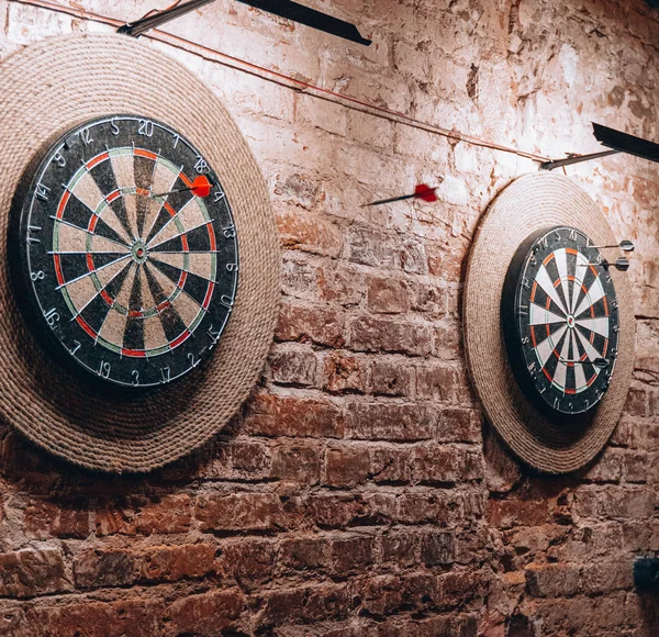 Two dartboards hanging on a brick wall